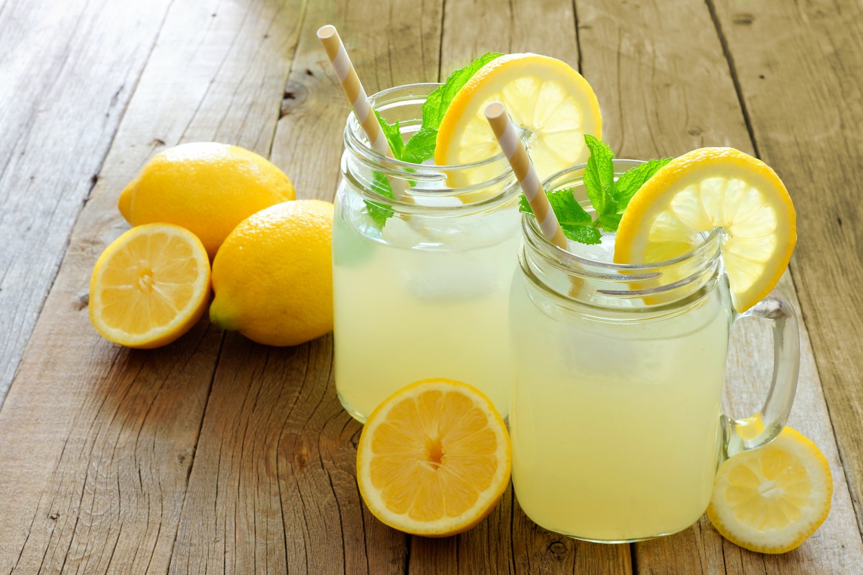 Mason jar glasses of homemade lemonade on rustic wood