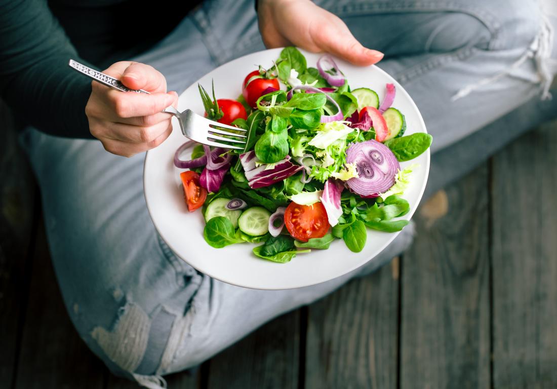 a-person-sitting-on-the-floor-eating-a-healthy-salad