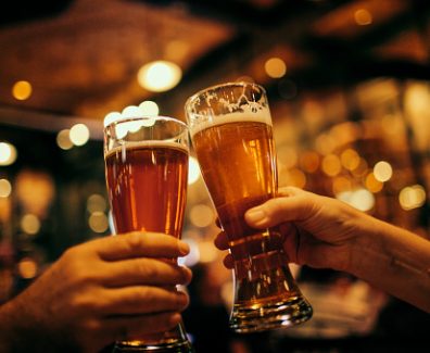 A couple celebrating cheering with two glasses of beer.