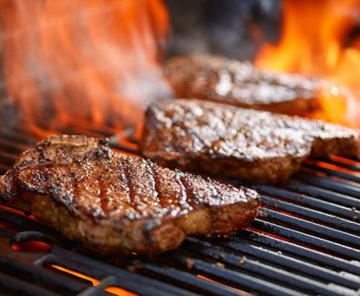 grilling steaks on flaming grill and shot with selective focus