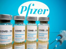 FILE PHOTO: Vials and medical syringe are seen in front of Pfizer logo in this illustration