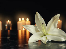 White,Lily,And,Blurred,Burning,Candles,On,Table,In,Darkness,