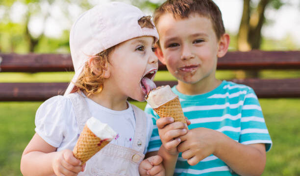 Cute little boy share ice cream with his sister