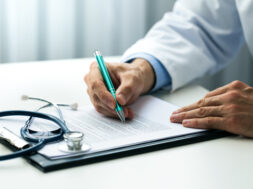 doctor writing documents at desk in clinics office