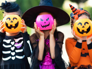 Happy Halloween! funny children in carnival costumes hide their heads behind buckets   pumpkins outdoors