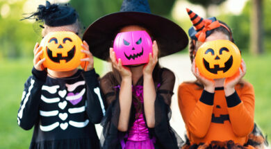 Happy Halloween! funny children in carnival costumes hide their heads behind buckets   pumpkins outdoors
