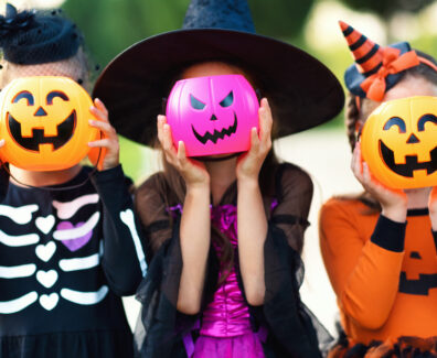 Happy Halloween! funny children in carnival costumes hide their heads behind buckets   pumpkins outdoors