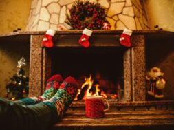 Someone-wearing-holiday-socks-relaxing-in-front-of-the-Christmas-decorated-fireplace-with-a-mug-of-hot-chocolate