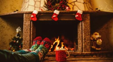 Someone-wearing-holiday-socks-relaxing-in-front-of-the-Christmas-decorated-fireplace-with-a-mug-of-hot-chocolate