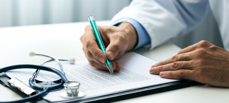 doctor writing documents at desk in clinics office