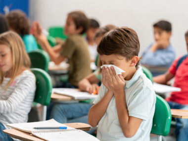 Sick boy at the school blowing his nose in class