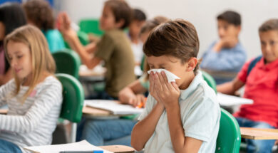 Sick boy at the school blowing his nose in class