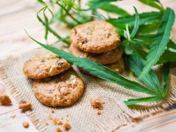 Cookies with cannabis leaf marijuana herb on sack wooden backgro