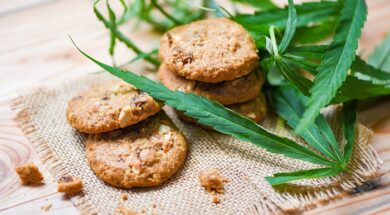 Cookies with cannabis leaf marijuana herb on sack wooden backgro