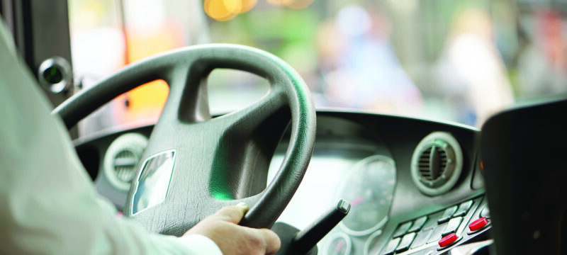 cropped shot of bus driver holding steering whee