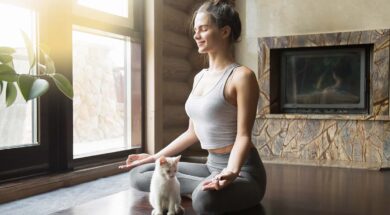 Young woman in Half Lotus pose at home with cat