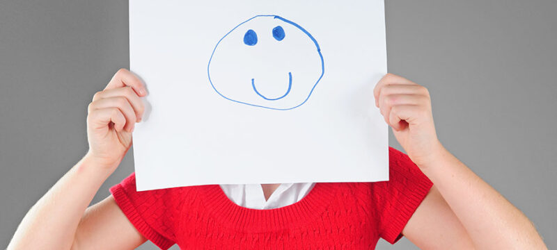 Girl hiding behind happy face