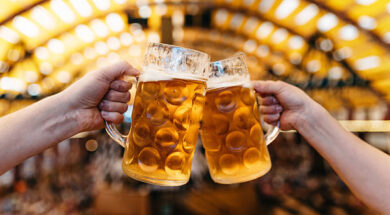 two hands clinking beer glasses in octoberfest marquee