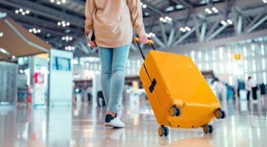 Young female traveler passenger walking with a yellow suitcase at the modern Airport Terminal, Woman on her way to flight boarding gate, Ready for travel or vacation journey