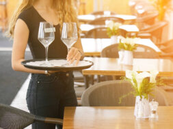 The waitress is carrying a wine glasses