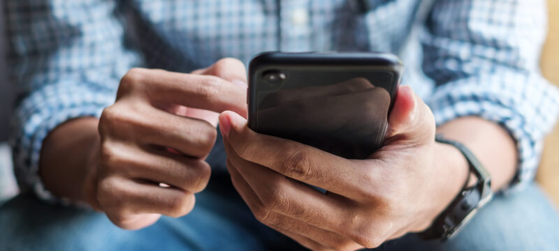 Young casual Businessman holding and using smartphone for sms me