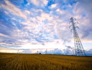 High voltage post with field and sky.