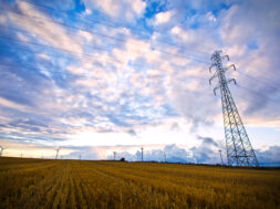 High voltage post with field and sky.